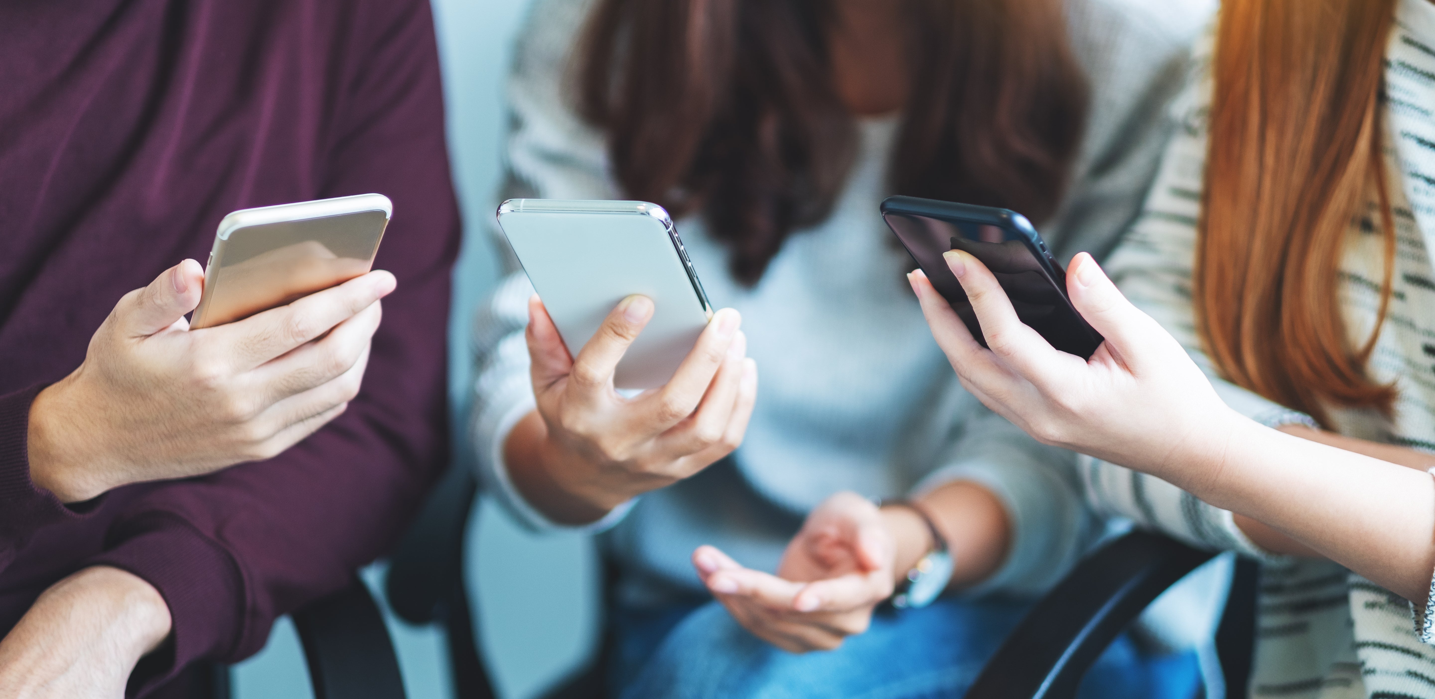 A group of people looking at their refurbished iPhones and Samsung phones